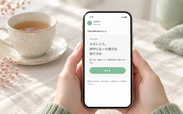 スマホに届いた今週の質問「小さいころ、夢中になった遊びは何ですか」を、両手で持って見ているところ